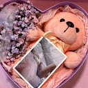 Teddy bear in a box with flowers